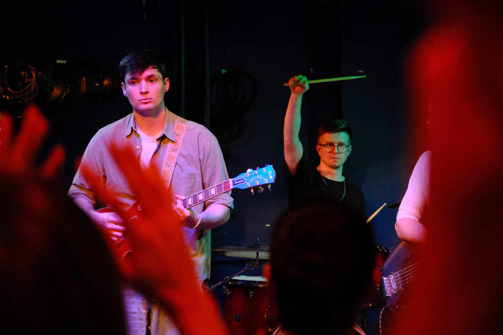 Guitarist and drummer mid-set under red stage light