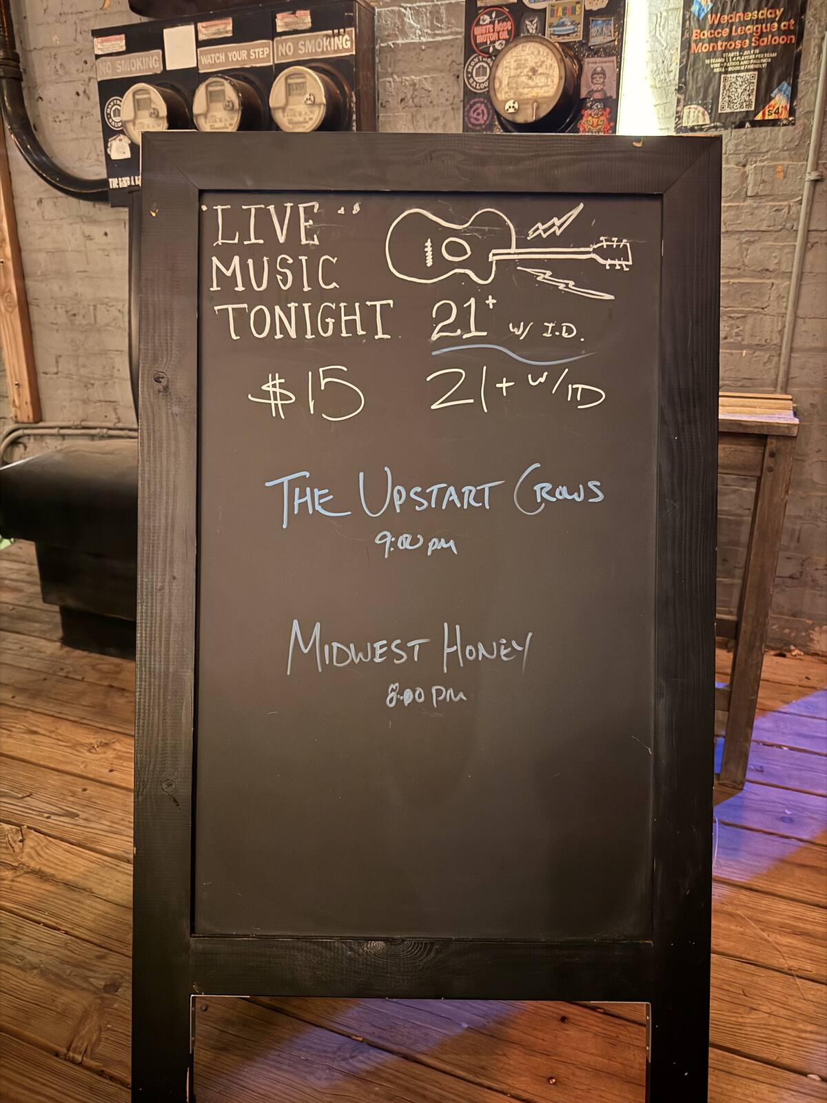 A sidewalk sign listing Midwest Honey at 8 PM